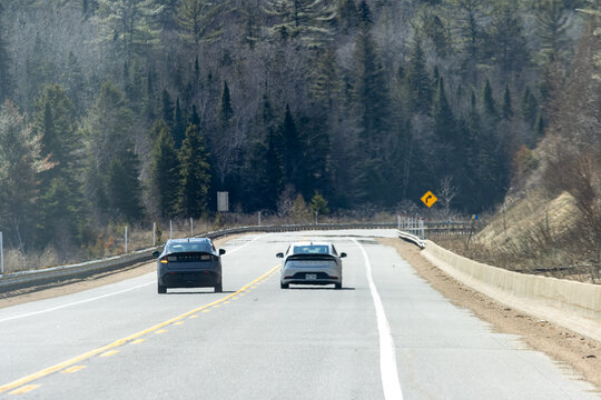 Quebec, Canada, 24 April 2026 : Two cars, a Hyundai Ioniq  and a Toyota Prius Prime, drive on a winding road through a forest.