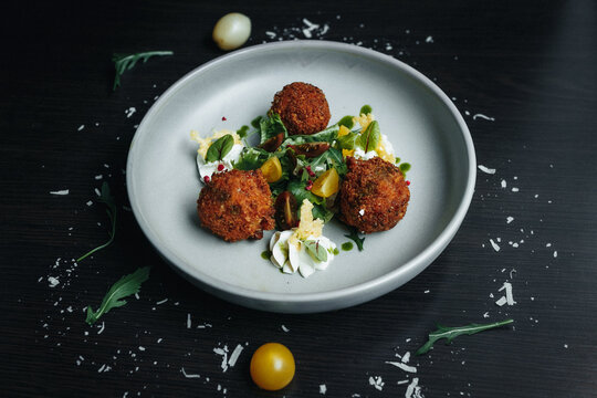 Fried meatballs with herbs and cherry tomatoes on a minimalist plate