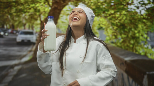 Woman chef holding a milk bottle pinches her nose and clutches her stomach while grimacing on a tree lined street; food safety disgust.