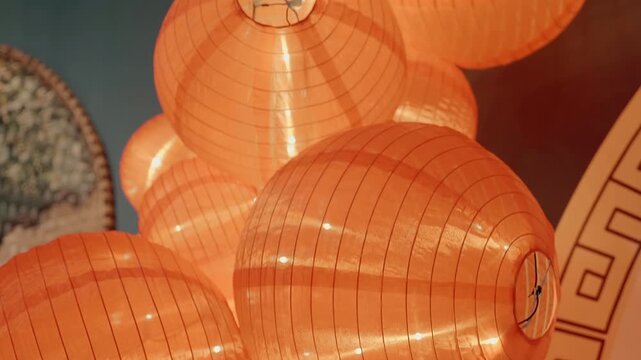 Large orange traditional Asian paper lanterns illuminated with tiny white LED diodes from inside are tied together creating a beautiful visual installation in Lumiere Light Garden in Da Lat, Vietnam
