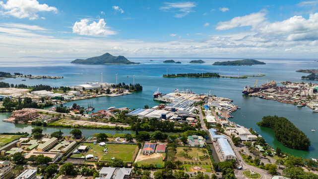 An industrial shipping port filled with containers, cranes, and cargo ships by the waterfront. Victoria. Seychelles, Mahe.