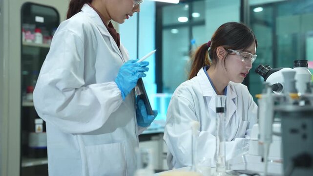 Team of biochemical research scientists using microscopes for vaccine development in a pharmaceutical laboratory, medical research and healthcare innovation.