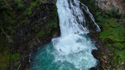 Majestic waterfall cascades into turquoise pool surrounded by lush greenery in a serene forest landscape © Tetiana