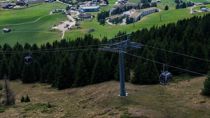 Scenic mountain gondola gliding over lush valleys and charming alpine villages in a sunlit summer afternoon © Tetiana