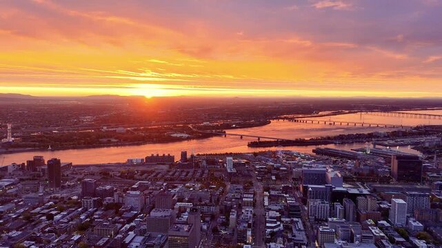 Vibrant sunrise over Montreal skyline with St Lawrence River and La Grande Roue reflecting colorful evening sky. g.