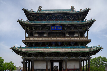 Obraz premium Ancient Chinese tower with ornate roof and blue signage under a cloudy sky