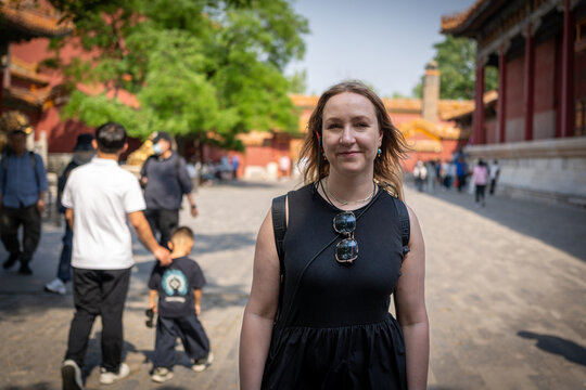 Woman smiling in front of historic Chinese architecture, a tourist destination