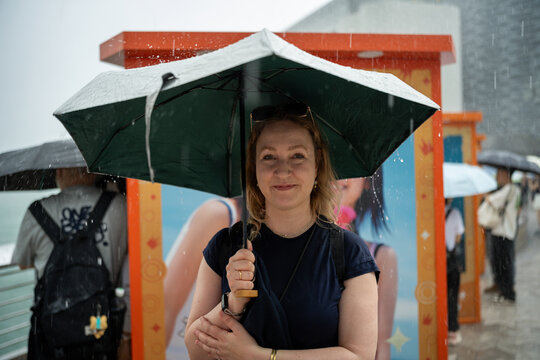 Woman holding umbrella in the rain with people in background