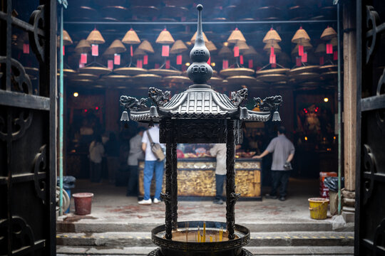 Traditional incense burner in a bustling Hong Kong temple with hanging coils