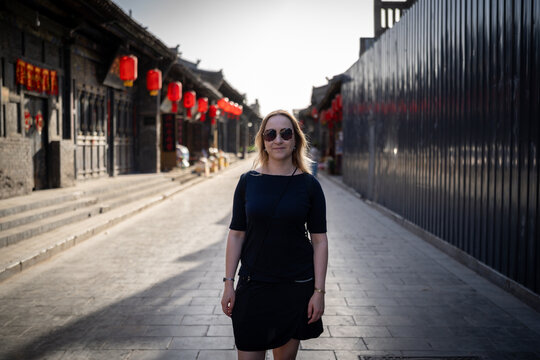 Woman in sunglasses standing on a cobblestone street in an ancient Chinese town