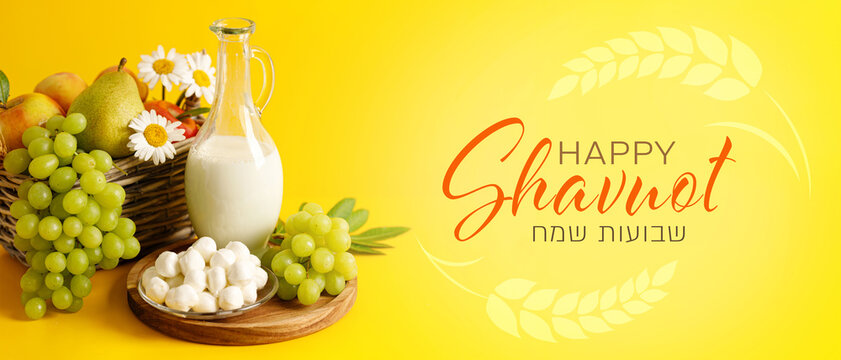 Wicker basket with fruits, wheat ears and dairy products on yellow background, Shavuot concept