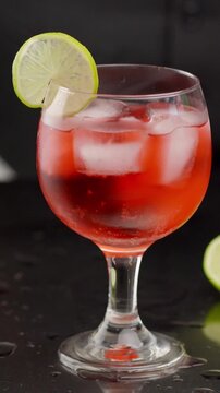 Cocktail glass with ice and bright lemon lime in the hands of a male bartender. blurred background