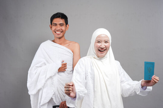 muslim pilgrims wife and husband wearing ihram and standing together ready for hajj, Umrah pointer passport. over isolated by grey background. Hajj concept. concep islam muslim concept