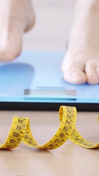 Closeup of tape measure and woman feet standing on weigh scales. Diet, weight loss and feet of a woman on a scale for body check, measure and balance to loseweight. Obesity, scales and girl with tape