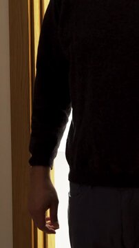 A dark room,a door opens with a silhouette of an unrecognisable man appears, he stands in the doorway, fists clenched.,Focus on shadow.Concept of roll up your sleeves.