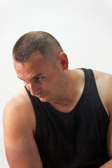 Naklejka premium Man with Short Buzz Cut Hair Looking Down Against Plain Background neutral grey studio wall.