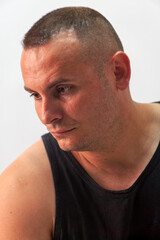 Naklejka premium Man with Short Buzz Cut Hair Looking Down Against Plain Background neutral grey studio wall.