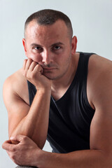 Naklejka premium Man with Short Buzz Cut Hair hand on the chin Against Plain Background neutral grey studio wall.