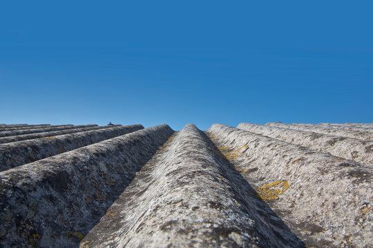 Old aged roof made of corrugated asbestos panels - dangerous materials in buildings and construction industry