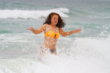 Fototapeta premium Refreshing Summer Swim Female Tourist Wading Through Sea Foam