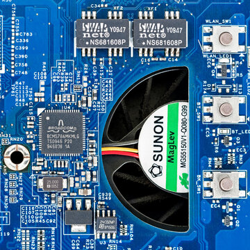 Close up of an Acer Aspire 5542 motherboard featuring the Broadcom BCM5784MKMLG Gigabit Ethernet controller chip beside a Sunon cooling fan on a blue PCB circuit board.