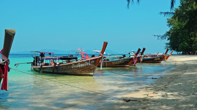Traditional wooden long-tail boats moored in crystal clear turquoise water at Ko Kradan beach, Trang province, Thailand, exotic travel destination, tropical summer vacation background