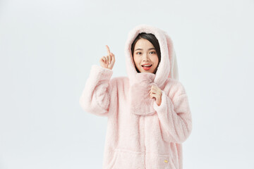 Cheerful young woman in pink hooded fleece pointing upward © KieuLan