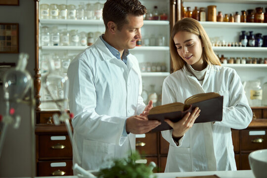 Happy students of science reading an old medical book in a laboratory