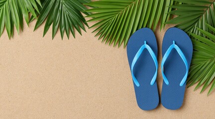 Fototapeta premium Blue flip flops on beach sand with green palm leaves and copy space