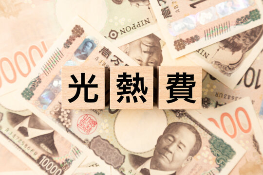 「光熱費」と書かれたブロックとたくさんの一万円札