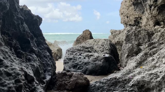 Scenic View of Ocean Waves Crashing on Coral Rocks Framed by Cave Opening