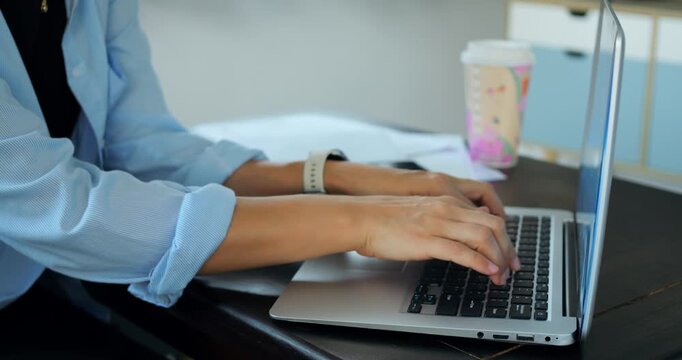 Person engaging in writing on personal computer. Individual focused on composing content at home workspace. Prolific writer working intently on laptop with coffee nearby in relaxed setting