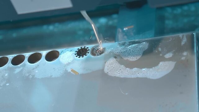 A complex part is cut out of a metal workpiece using a wire-cut electrical discharge machine (Wire EDM). Closeup