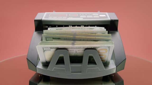 Money Counter Machine Counting Dollar Bills on Pink