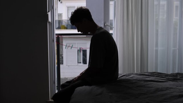 Broken hearted man sitting alone in dark room after breakup. 