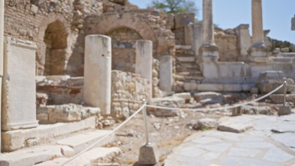 Fototapeta premium Ancient stone ruins and weathered marble columns lining a sunlit path, softly blurred outdoor background; background backdrop copyspace calm.