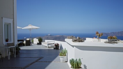Fototapeta premium Sunlit seaside terrace with defocused foreground, soft bokeh sea and white architecture, outdoor; background backdrop copyspace calm.