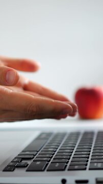 Closeup hands typing on laptop keyboard, apple blurred in background, remote worker tapping keys for writing and content creation, clean minimal desk, soft natural light, focused productive mood