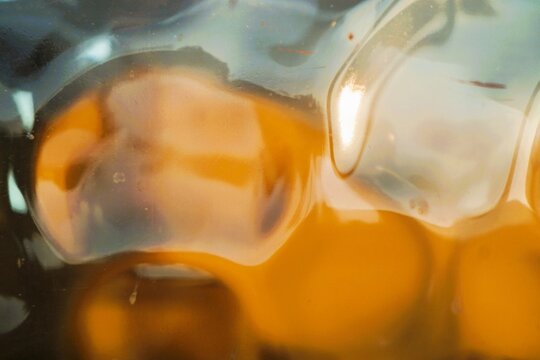 Abstraktes Motiv mit goldbraun-blau-wei&szlig;em Glasmuster mit Licht als Hintergrund