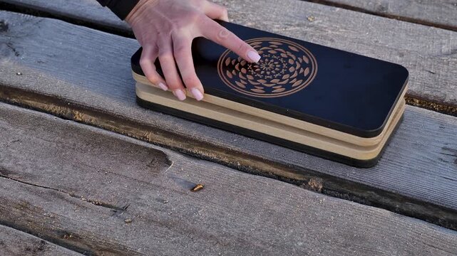 Close up of female hands opening a professional Sadhu board with sharp metal nails on a wooden background. Concept of meditation, alternative medicine, yoga practice and pain management