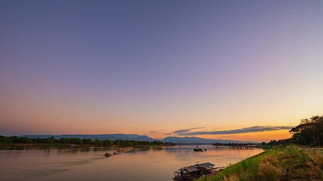 Time lapse A dreamlike sunset casting golden light over the Mekong River and the Fifth Thai&ndash;Lao Friendship Bridge in Bueng Kan, creating a surreal and peaceful atmosphere. colorful Reflection