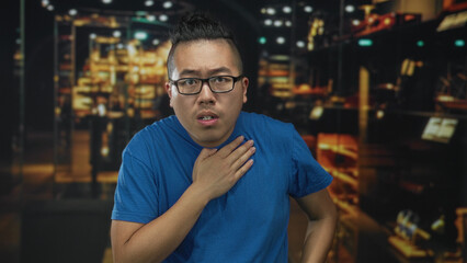 Obraz premium Man clutching chest for heartattack in museum building while pointing to his chest with fingers; anxiety concern.