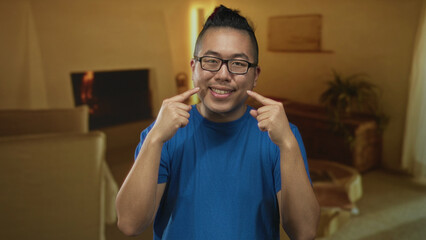 Obraz premium Man pointing fingers to cheeks in building living room scene showing smile and glasses; warm domestic happiness.