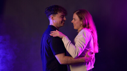 Obraz premium Couple dancing and embracing, happy and romantic, against a background of purple and pink neon light