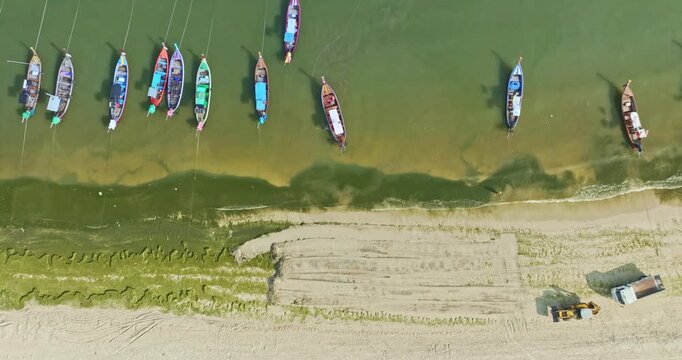 Top view of algae forming along the sandy coast of Patong Beach with machinery working to restore the shoreline. A striking blend of natural textures and industrial activity in a seaside environment