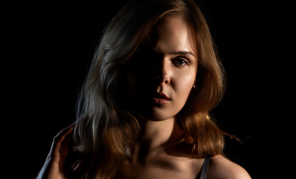 Woman posing in shadow and light, creating a mysterious and captivating dramatic portrait