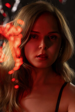 Young woman contemplating in dramatic low key red and bokeh light