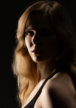 Blonde woman posing in low key lighting, with a dramatic and moody expression