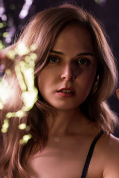 Young woman with blonde hair and blue eyes posing with dramatic lighting and bokeh