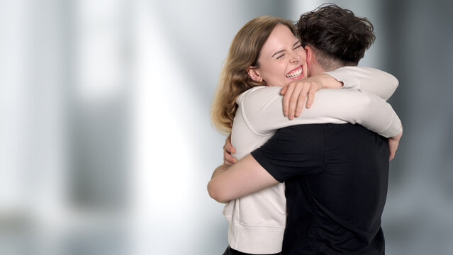 Young woman laughing while hugging man, showing happiness and emotional connection